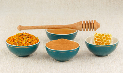 Honey, honeycomb, pollen granules and cinnamon in bowls