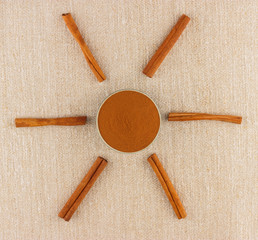 Ground cinnamon in bowl and cinnamon sticks