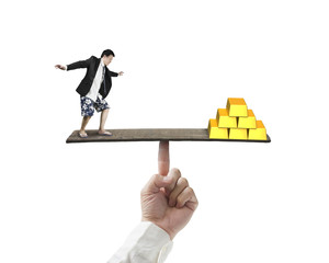 businessman standing on finger seesaw vs stack of gold