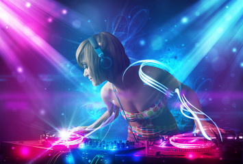 Fototapeta na wymiar Energetic Dj girl mixing music with powerful light effects