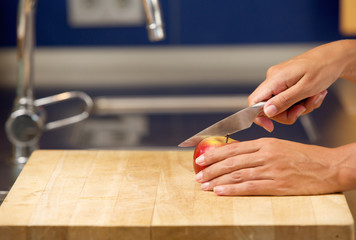 Obraz premium Female hands cutting apple on chopping board
