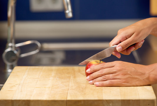 Female hands cutting apple on chopping board