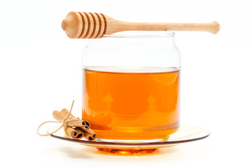 Honey in jar with dipper and cinnamon on isolated background