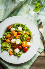 Salad with arugula,tomatoes and mozarella on wooden background