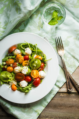 Salad with arugula,tomatoes and mozarella on wooden background