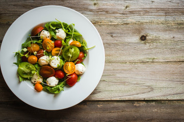 Salad with arugula,tomatoes and mozarella on wooden background