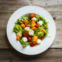 Salad with arugula,tomatoes and mozarella on wooden background