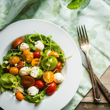 Salad with arugula,tomatoes and mozarella on wooden background