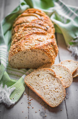 Sliced loaf of seeded bread on wooden background