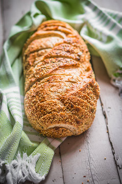 Sliced loaf of seeded bread on wooden background