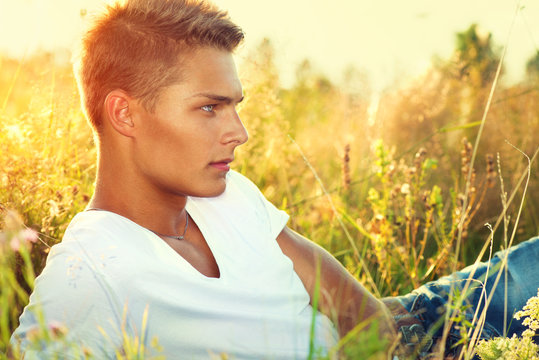 Handsome guy lying on the field. Young man enjoying nature