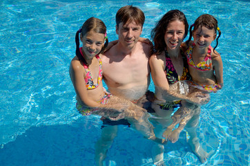 Happy family with  two kids in swimming pool. Summer vacation