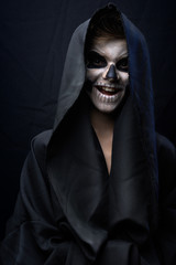 Teen with make-up of skull in black cloak laughs