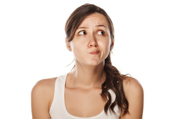 confused young woman posing on a white background - obrazy, fototapety, plakaty