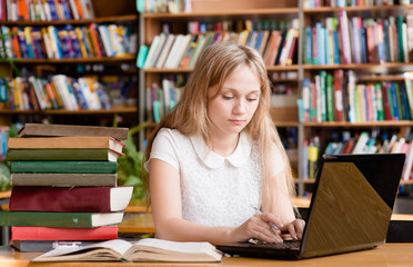 pretty female student  typing on notebook in library