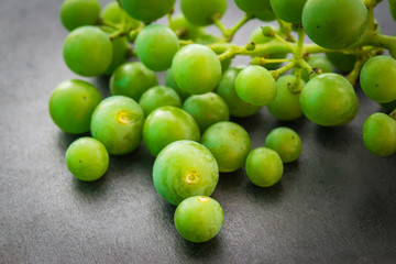 Unripe green grapes on dark background. Selective focus.