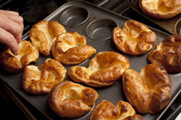 Man removing Yorkshire puddings from a baking tray