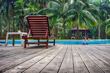 Wooden sunbath chair and side table in swimming pool