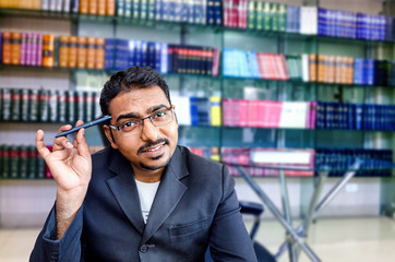 portrait of happy businessman at office library with pen