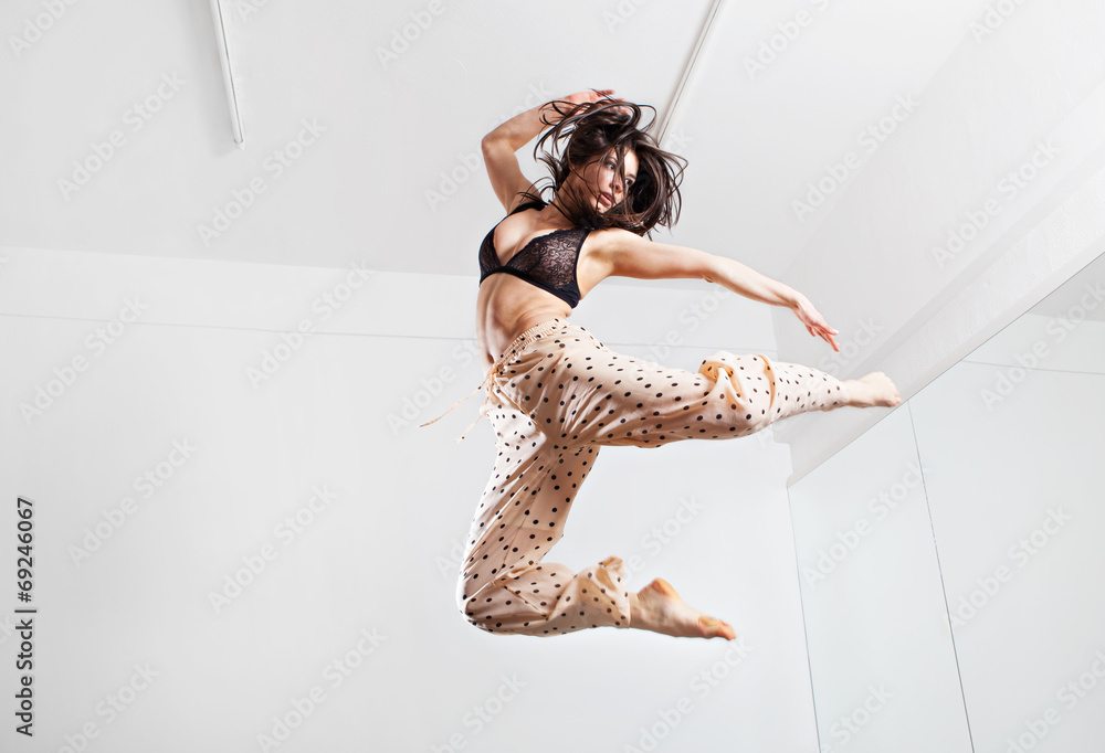 Wall mural Jumping young woman on a trampoline