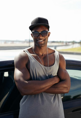 Stylised young muscular man leaning against car