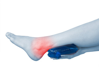 Acute pain in ankle. Woman holding hand to spot of ankle-aches.