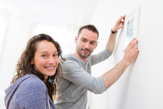 Couple hanging a painting in their new flat
