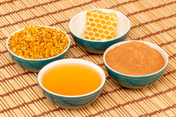 Honey, honeycomb, pollen and cinnamon in bowls