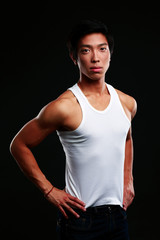 Fototapeta premium Portrait of a serious muscular asian man on black background