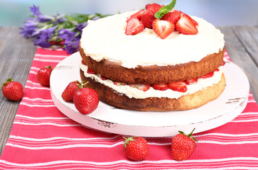 Delicious biscuit cake with strawberries on table close-up