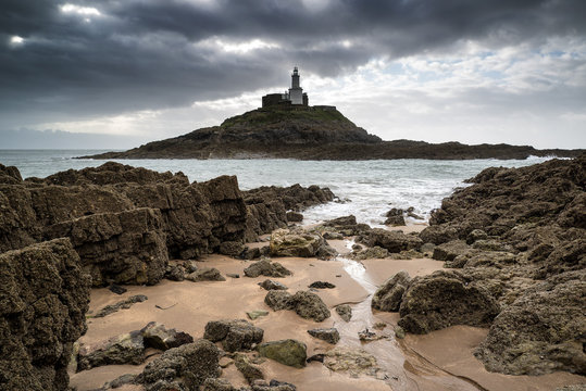 Lighthouse landscape with stormy sky over sea with rocks in fore