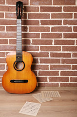 Obraz premium Guitar on the floor on brick wall background