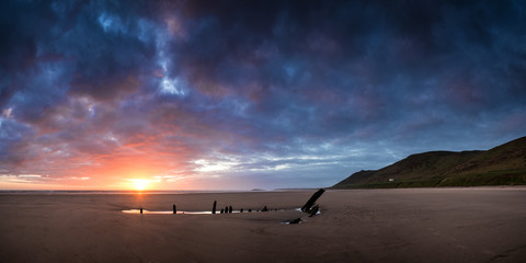 Landscape image of shipwreck on beach at Summer sunset