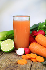 Fresh carrot juice with vegetables on wooden table