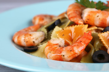 Fresh prawns with coloured macaroni and olives in a blue plate