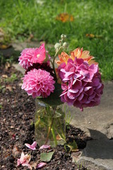 Sommerblumen im Wasserglas auf Friedhof