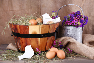 Big round basket with dried grass and fresh eggs