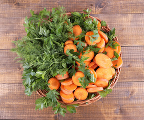 Slices of carrot and parsley in wicker bowl on wooden