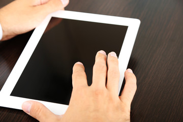 Man working on tablet on wooden background closeup
