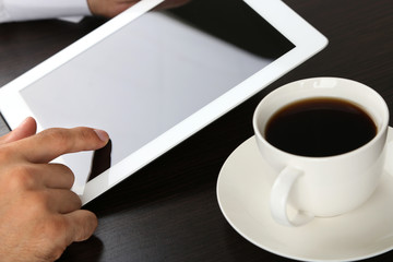 Man working on tablet on wooden background closeup