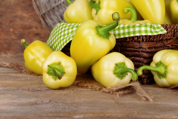 Yellow peppers in basket on wicker background