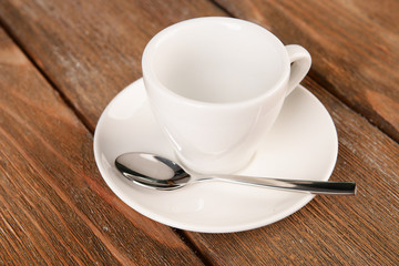 Empty cup with tea spoon on wooden background
