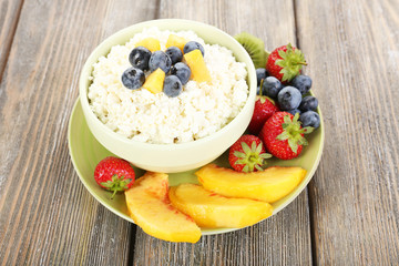 Cottage cheese with fruits and berries in bowl on wooden table