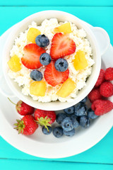 Cottage cheese with fruits and berries in bowl on wooden table