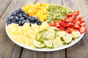 Sliced fruits on plate on wooden table
