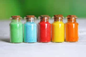 Bottles with colorful dry pigments on wooden background