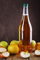 bottle of apple vinegar with fresh apples on wooden table