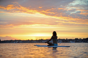 Naklejka na ściany i meble Frau auf Surfboard bei Sonnenaufgang