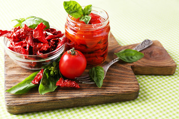 Sun dried tomatoes in glass jar, basil leaves