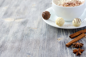 Pralines and a cup of cappuccino copy space wooden background